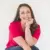 Smiling woman in red shirt against white background.