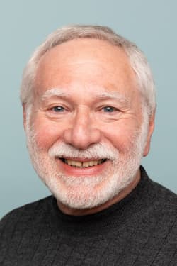 Smiling older man with gray hair and beard.
